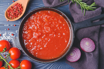 Frying pan with organic tomato sauce on wooden background