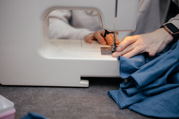 girl master sews on a sewing machine bedding in a sewing workshop.