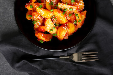 Plate with honey chilli potato on dark background