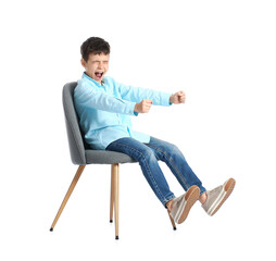 Little boy with imaginary steering wheel sitting in chair on white background