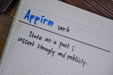 Affirm verb write on a book isolated on Wooden Table.