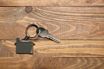 Key with house shaped keychain on wooden background