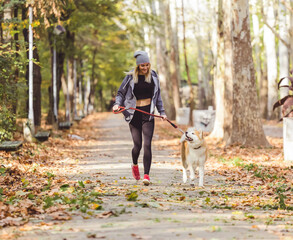 Fototapeta premium girl running and walking in beautiful park with akita dog.