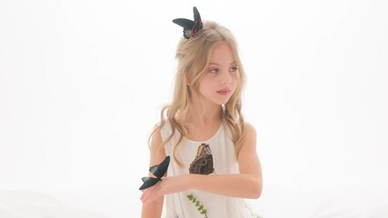 Portrait of a cute beautiful girl with butterflies in her hands on a white background in the studio.