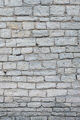 old brick wall made of limestone blocks of different sizes as the background