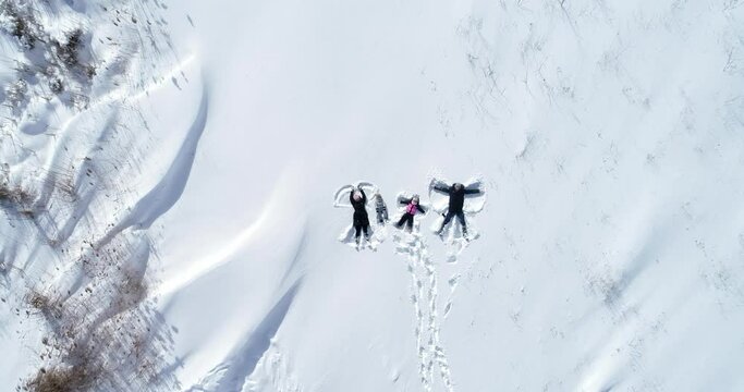 happy family lies in the snow and makes an angel