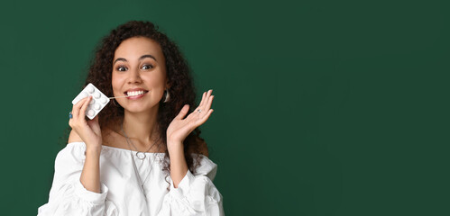 Happy African-American woman with chewing gum on color background