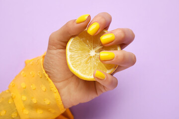Woman with trendy manicure holding sliced lemon on purple background