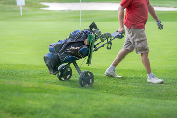 man pull golf bag on trundler