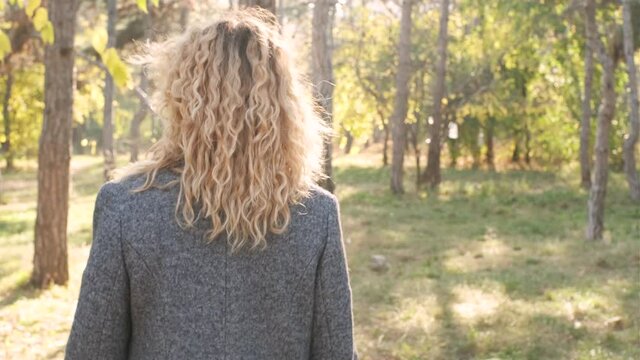 Portrait of young attractive curly woman walking in the autumn  park on a sunny day