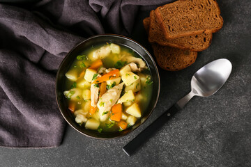 Bowl of tasty dumpling soup and bread on dark background
