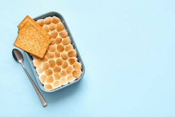Baking dish with tasty S'mores dip and crackers on blue background