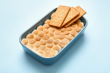 Baking dish with tasty S'mores dip and crackers on blue background