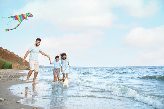 Happy family flying kite on sea beach