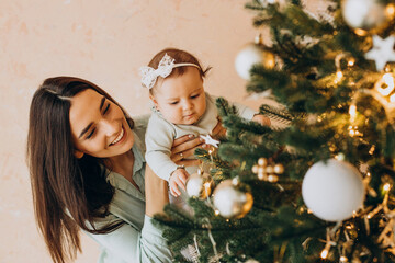 Mother with baby daughter dacorating christmas tree - Powered by Adobe