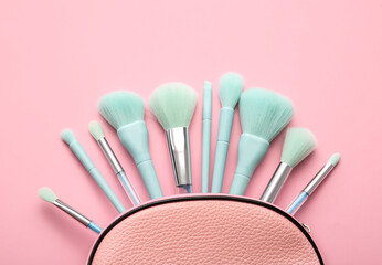 Cosmetic bag with stylish makeup brushes on pink background