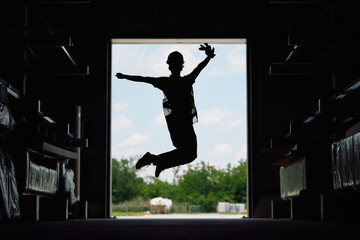 Silhouette of warehouse worker jumps of joy at storage compartment.