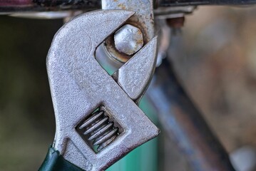 one gray adjustable wrench tightens a screw on the handlebars of an old bicycle