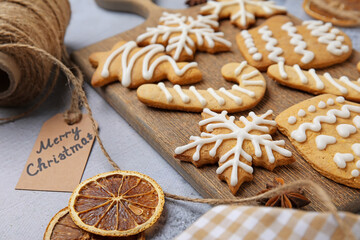 Board with Christmas gingerbread cookies on light background