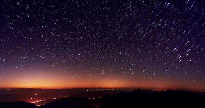 The stars are spinning in the starry night sky over the mountains, startrails