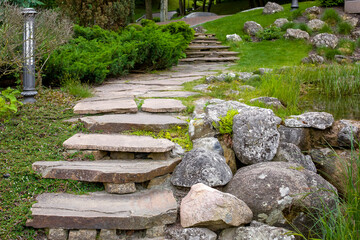 stone staircase with steps made of wild natural stone on slope of hill park landscape with bushes...