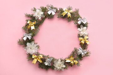 Frame made of fir branches and bows on pink background