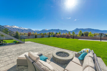 Outdoor patio with a view of a large backyard with basketball court against the mountain range view