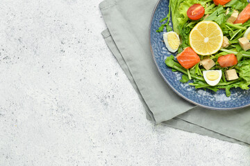 Fresh salad with salmon and vegetables in plate on light background
