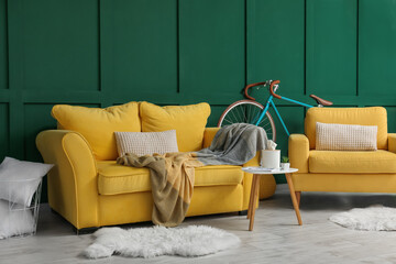 Interior of living room with yellow sofa, armchair and bicycle