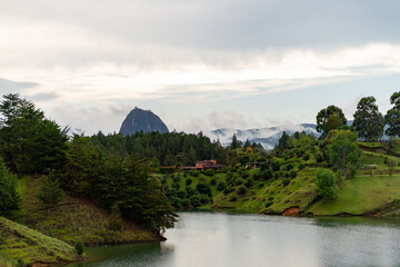 panoramic of nature landscape with lake, villa, and huge boulder in background