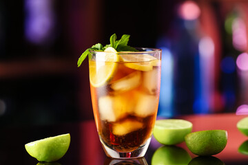 Glass of tasty Cuba Libre cocktail with mint on table in bar