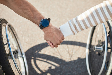 Obraz premium Close up of adult couple in wheelchairs holding hands outdoors, love and support concept, copy space