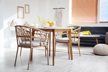 Dining table with oranges and wicker chairs in light room