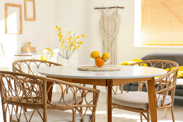 Dining table with oranges and wicker chairs in light room
