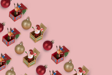 Cute Pattern with Reindeer and Santa Clause in a gift box and Christmas bauble balls on a pastel pink background.