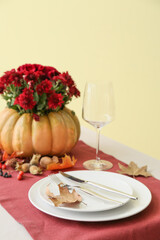 Plate with autumn leaf on served table near beige wall