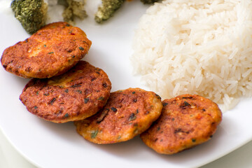 Chicken meatballs with rice and broccoli salad on a white plate
