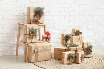 Stepladder with Christmas gift boxes and fir branches near white brick wall