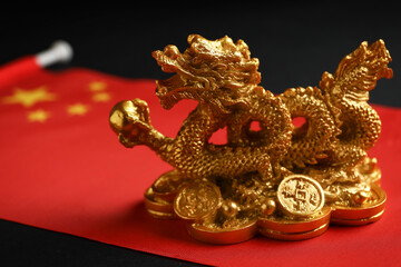 Figurine of dragon and Chinese flag on dark background