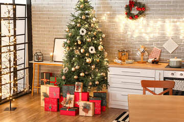 Christmas tree, gift boxes and decor near brick wall in kitchen