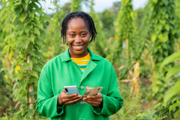 Successful African farmer calculating her income on the phone calculator
