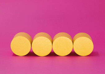 four yellow cylinders on a pink background - copy space