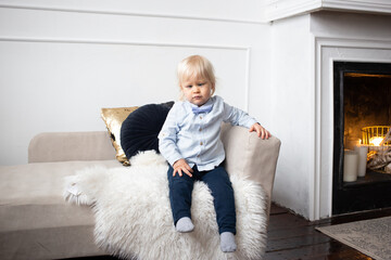 Cute little child sitting on sofa at home. people, children, rest and comfort concept.