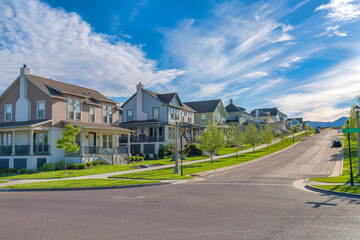 Row of large two-storey houses near the paved uphill road at Daybreak, Utah