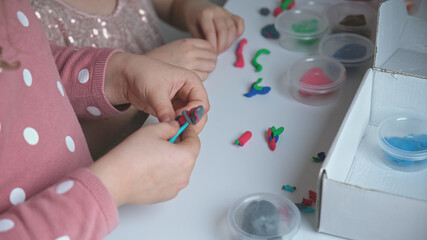 Two Creative Caucasian Girls Playing with Plasticine and Modeling Clay