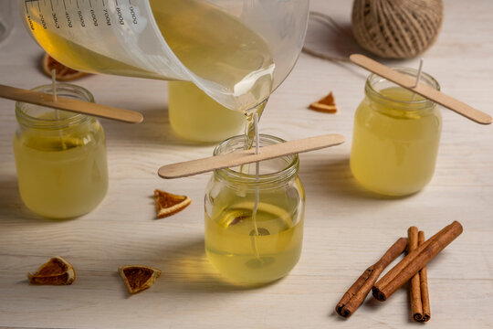 Set for crafting candle on wooden background. Pouring soy eax into glass. Eco soy wax on white table. DIY candle. Hobby concept.