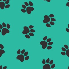 Fototapeta premium black footprints of a cat on a green background. seamless abstraction of animal footprints for clothing or print