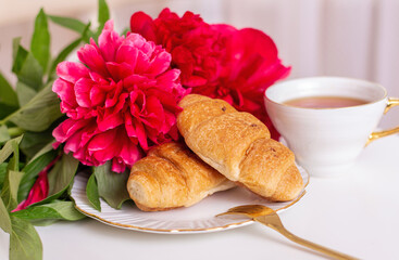
Cup of tea and croissants with hydrangea flowers on white table
