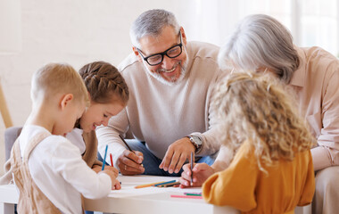Smiling senior couple grandparents spending time with grandchildren at home on weekend