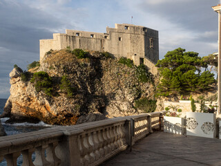 Sun lights wall of fortress perched on cliff in Dubrovnik. Croatia. 